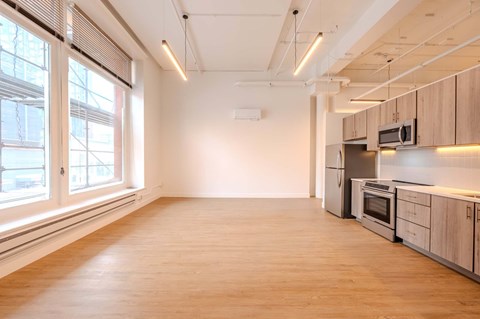 A spacious kitchen with wooden floors and stainless steel appliances.