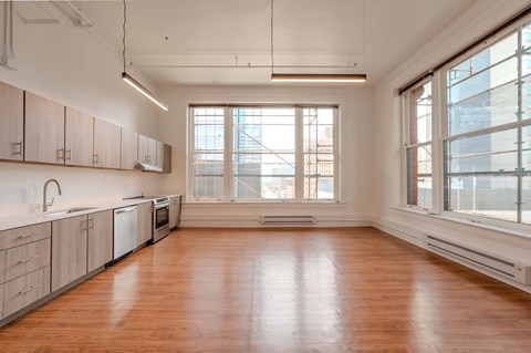 A large empty room with wooden floors and a window overlooking a cityscape.