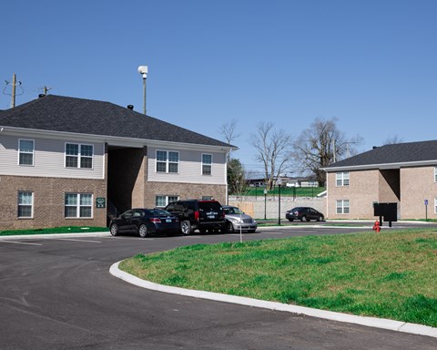 a parking lot in front of two buildings with cars parked