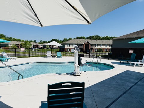 A pool area with a chair and umbrella.