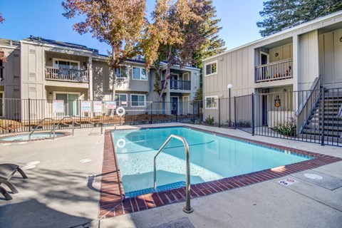 A small pool surrounded by a fence and apartment buildings.