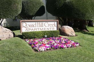a sign for pound creek apartments in front of a garden of flowers