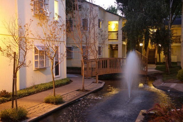 a fountain in front of a building with a pond