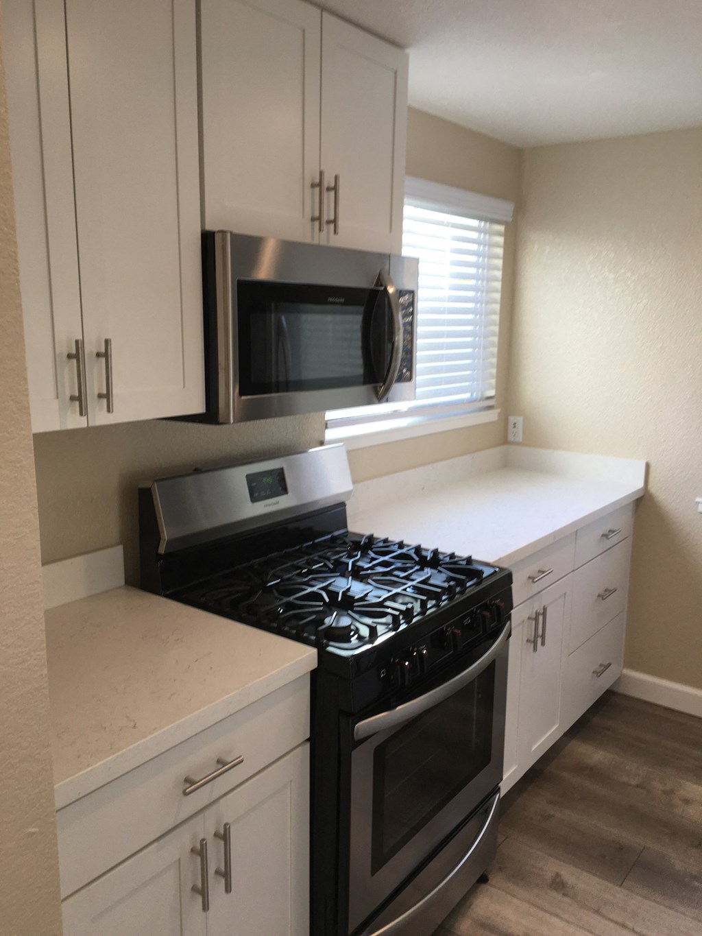 a kitchen with white cabinets and a stove and a microwave