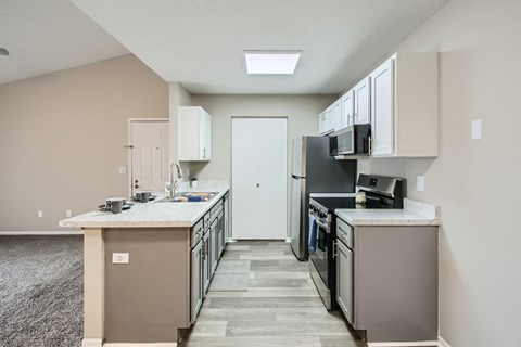 A kitchen with a white counter top and a black fridge.