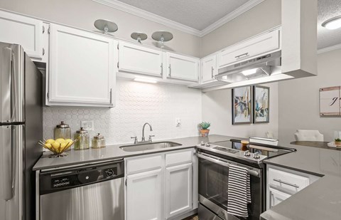 A modern kitchen with white cabinets and stainless steel appliances.