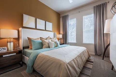 Spacious bedroom with plush carpeting, large windows, ceiling fan, and modern décor.