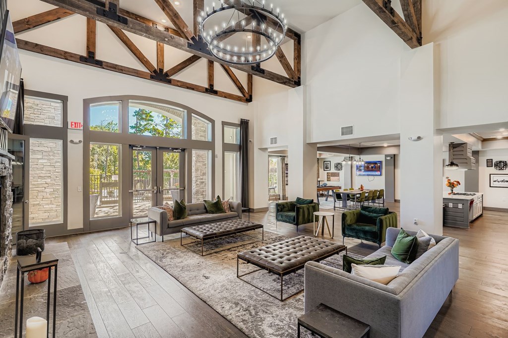 A large, open-concept living room with a high ceiling and wooden beams.