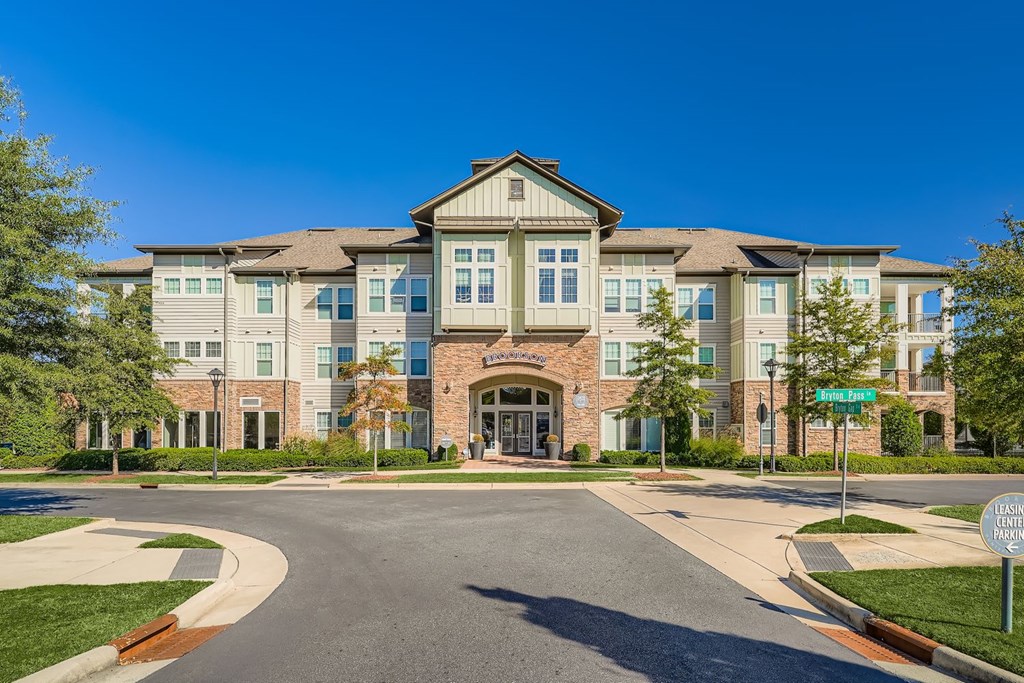 A large, modern building with a stone facade and a green lawn in front.
