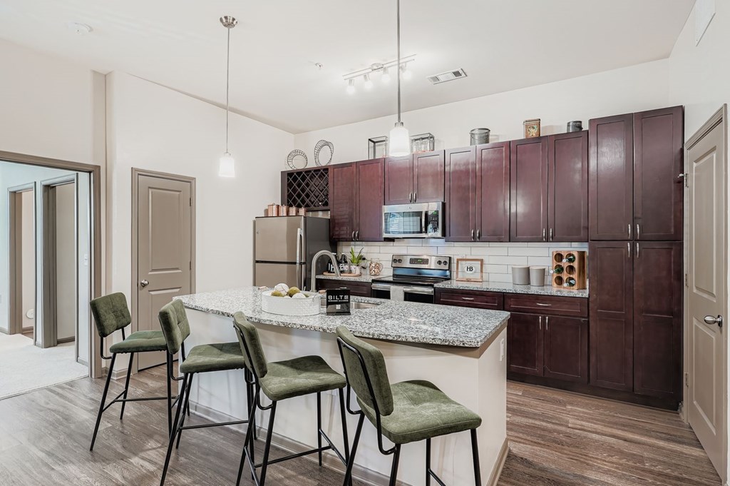 A kitchen with a granite countertop and green chairs.