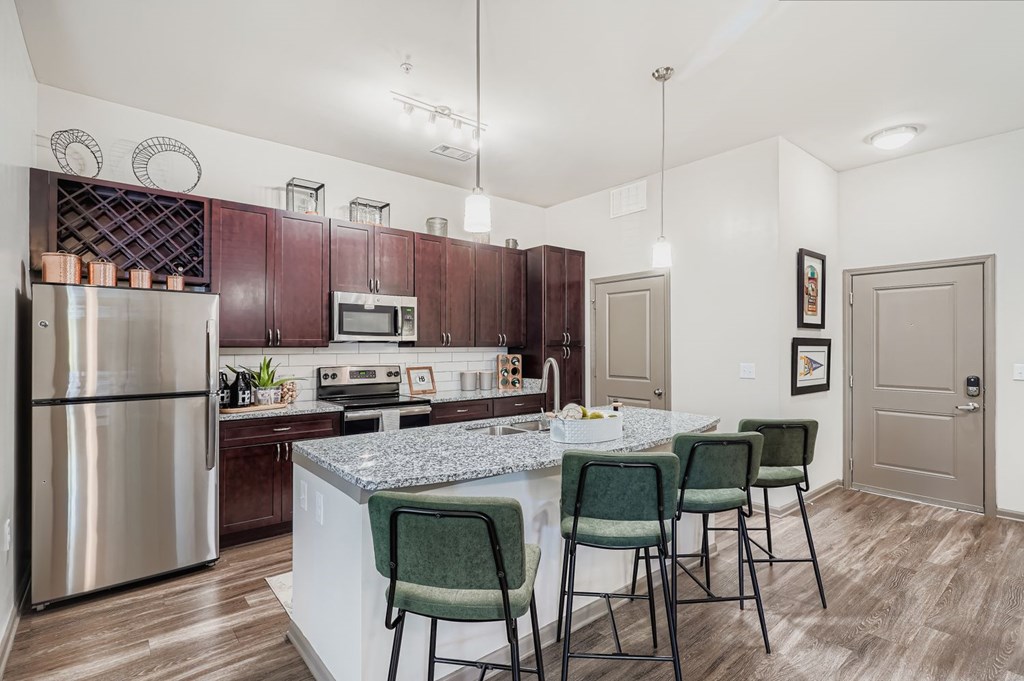 A kitchen with a marble countertop and green chairs.