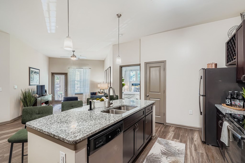 A kitchen with a granite countertop and a black refrigerator.