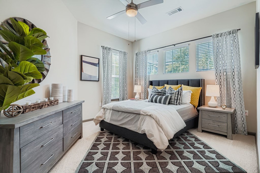 A bedroom with a bed, nightstand, and a plant.