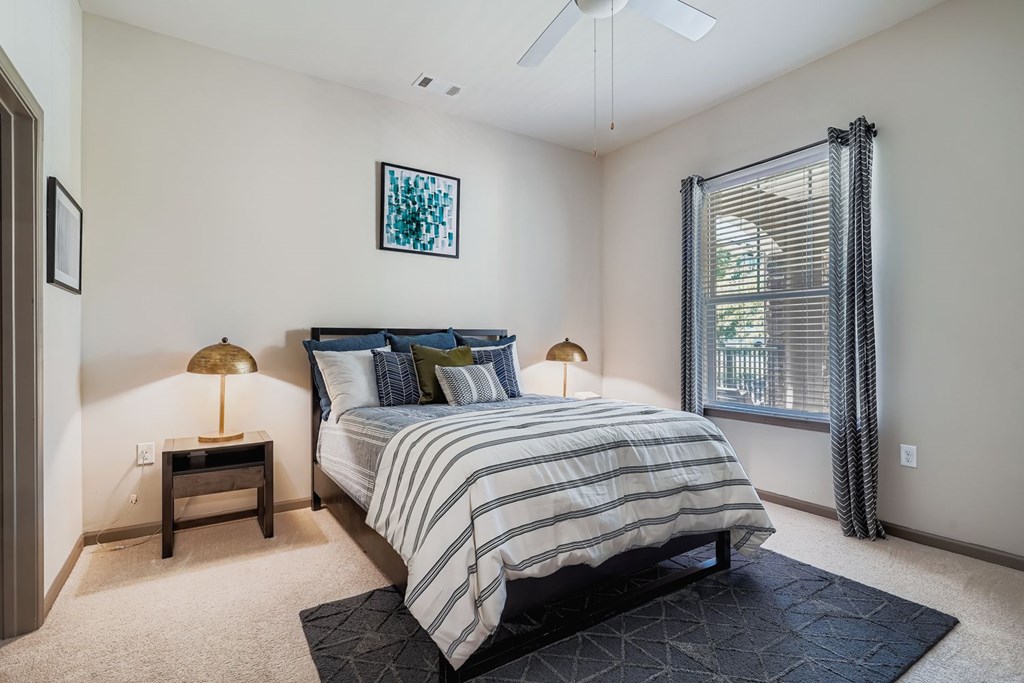 A bedroom with a bed, nightstands, and a ceiling fan.