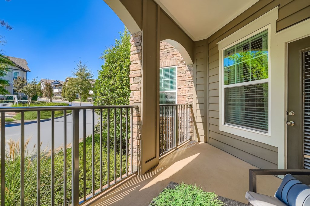 A balcony with a metal railing and a window overlooking a body of water.