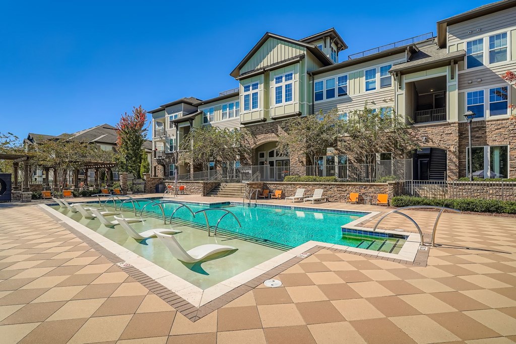 A large swimming pool in front of a building with a tiled floor.