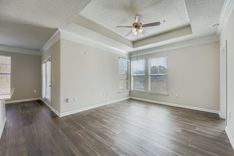 A spacious room with wooden floors and a ceiling fan.