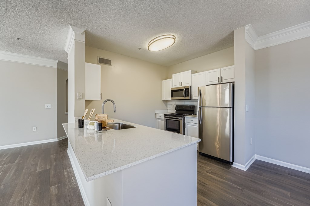 A kitchen with a white countertop and stainless steel appliances.