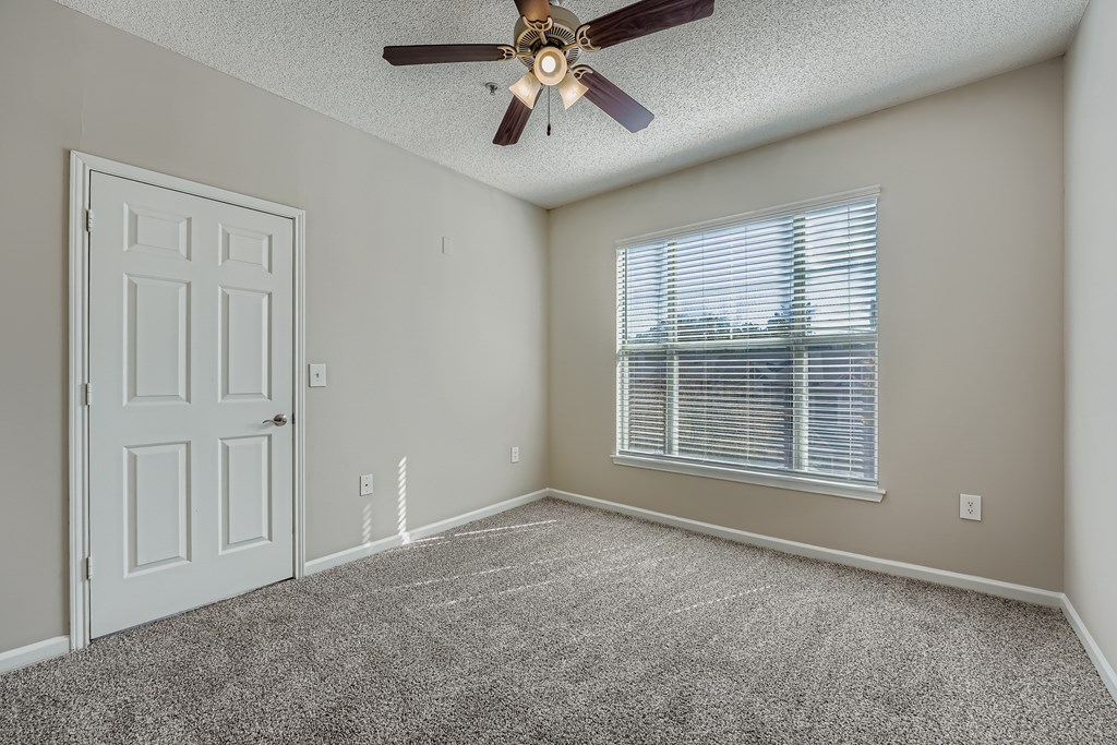 A room with a ceiling fan and a window with blinds.