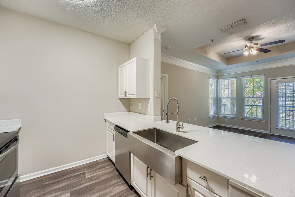 A kitchen with a stainless steel sink and white cabinets.
