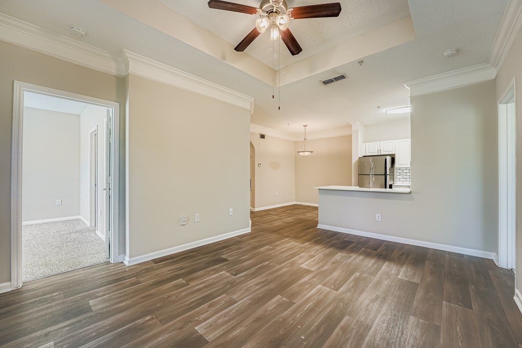 A room with a ceiling fan and wooden flooring.