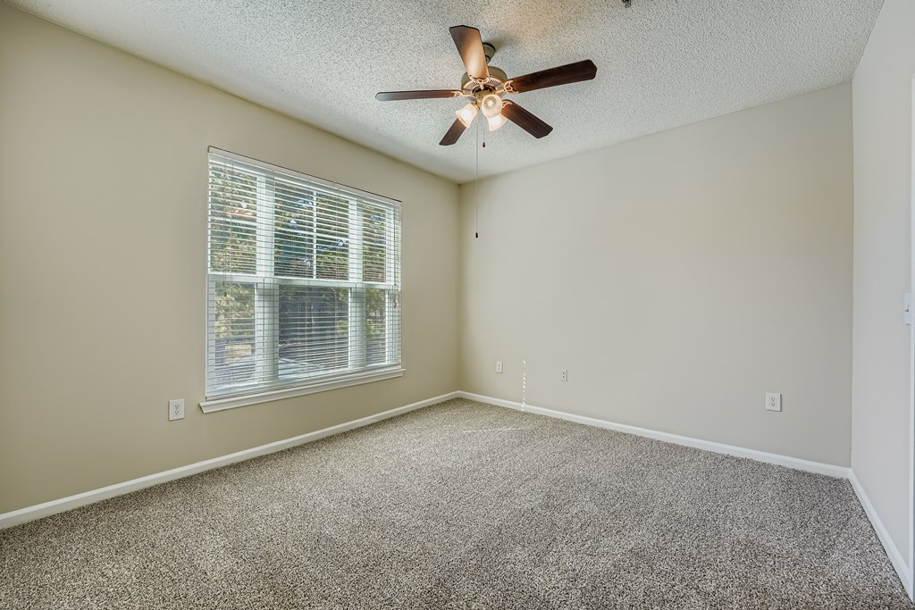 A room with a ceiling fan and a window with blinds.