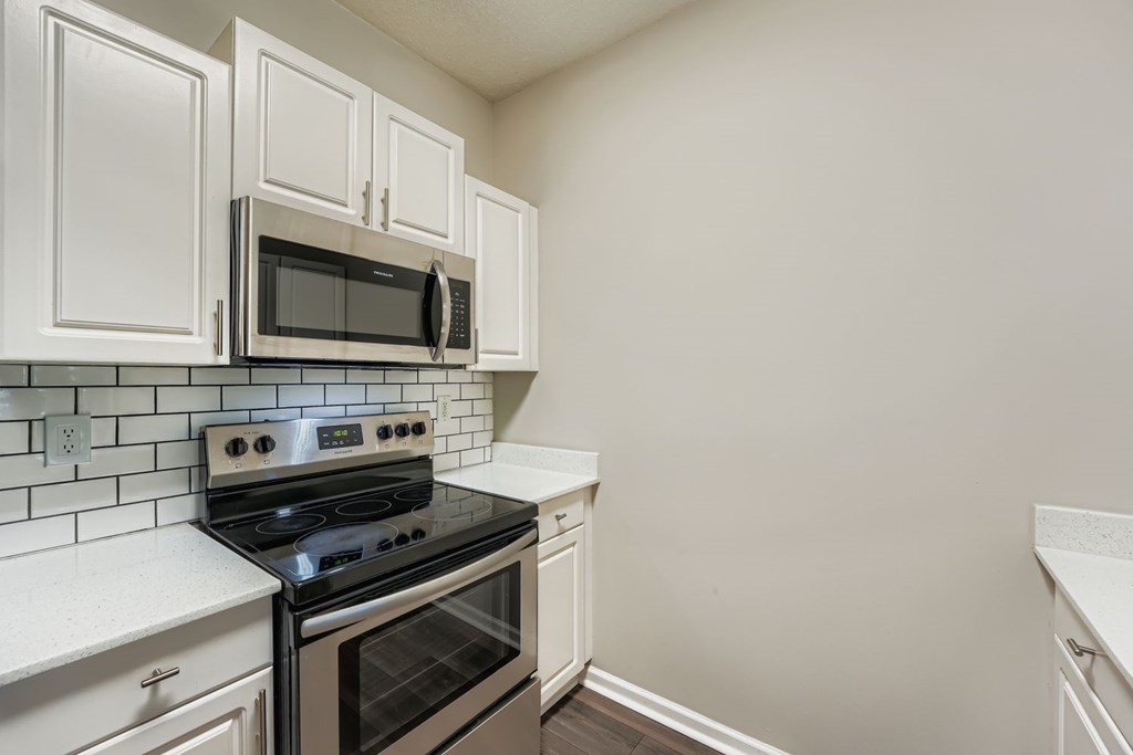A kitchen with white cabinets and a black stove top oven.