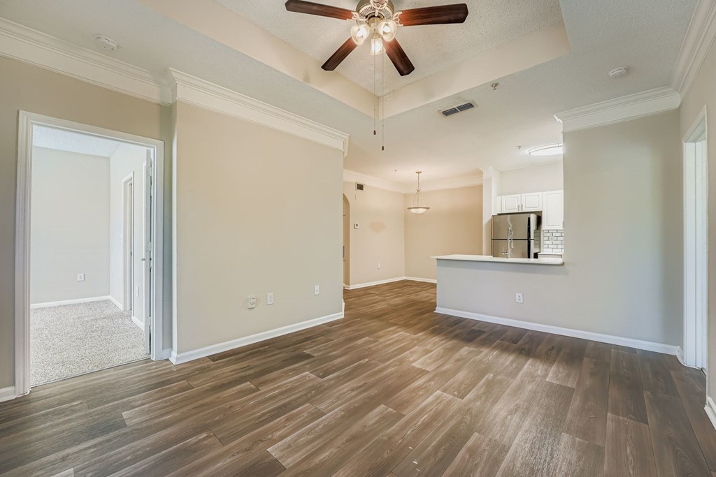 A room with a ceiling fan and wooden flooring.