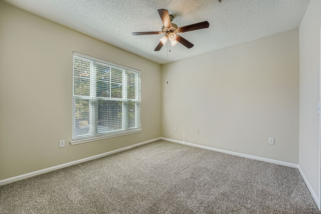 A room with a ceiling fan and a window with blinds.