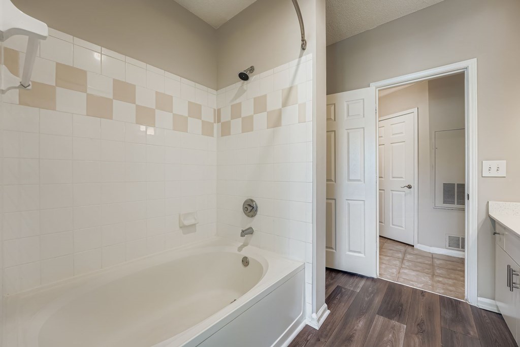 A bathroom with a tub and a doorway leading to another room.