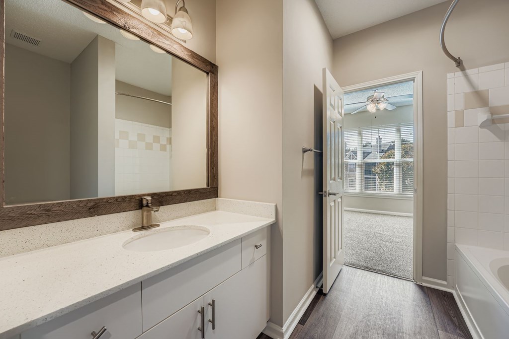 A bathroom with a sink, mirror, and bathtub.