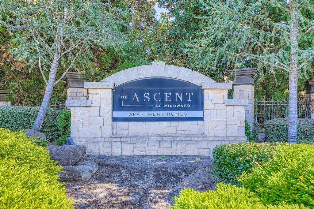 A sign that says "The Ascent Apartment Homes" is in front of some trees.