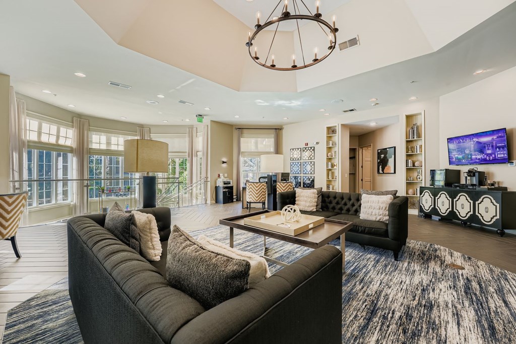 A modern living room with a large grey sofa and a chandelier.