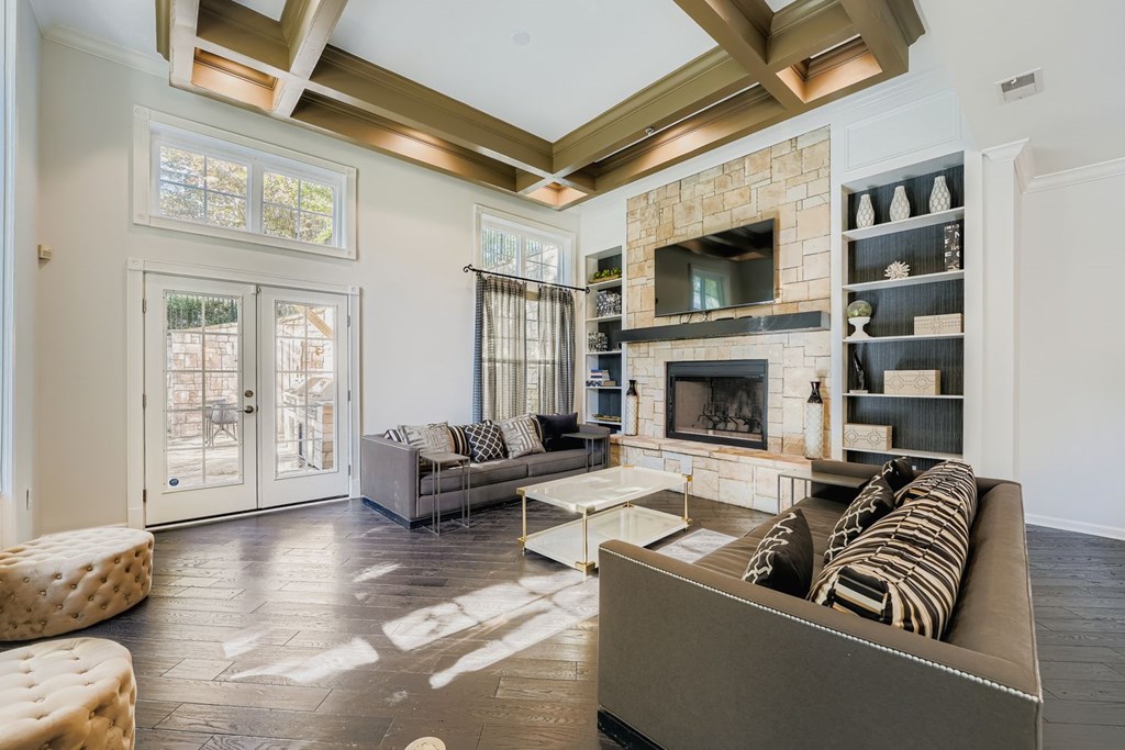 A living room with a stone fireplace and a grey couch.