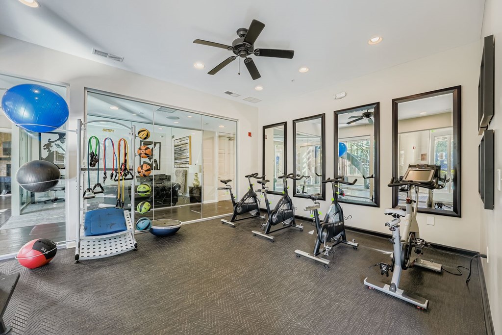 A spacious gym with a variety of exercise equipment and mirrors on the wall.