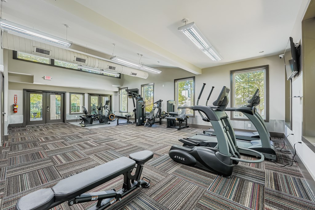 A gym with a variety of equipment including treadmills, exercise bikes, and weights.