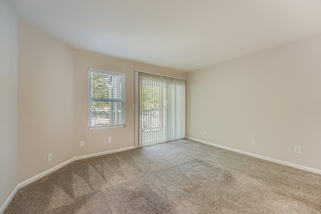 A room with a carpeted floor and a sliding glass door.