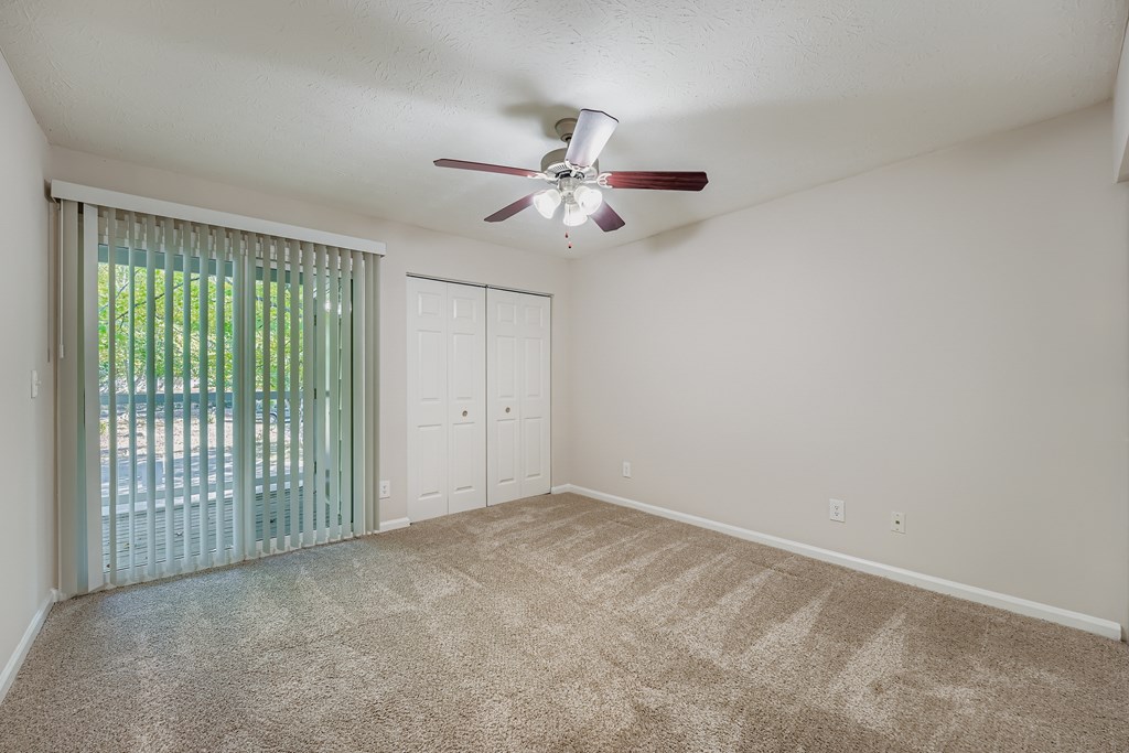 A room with a ceiling fan and carpeted floor.