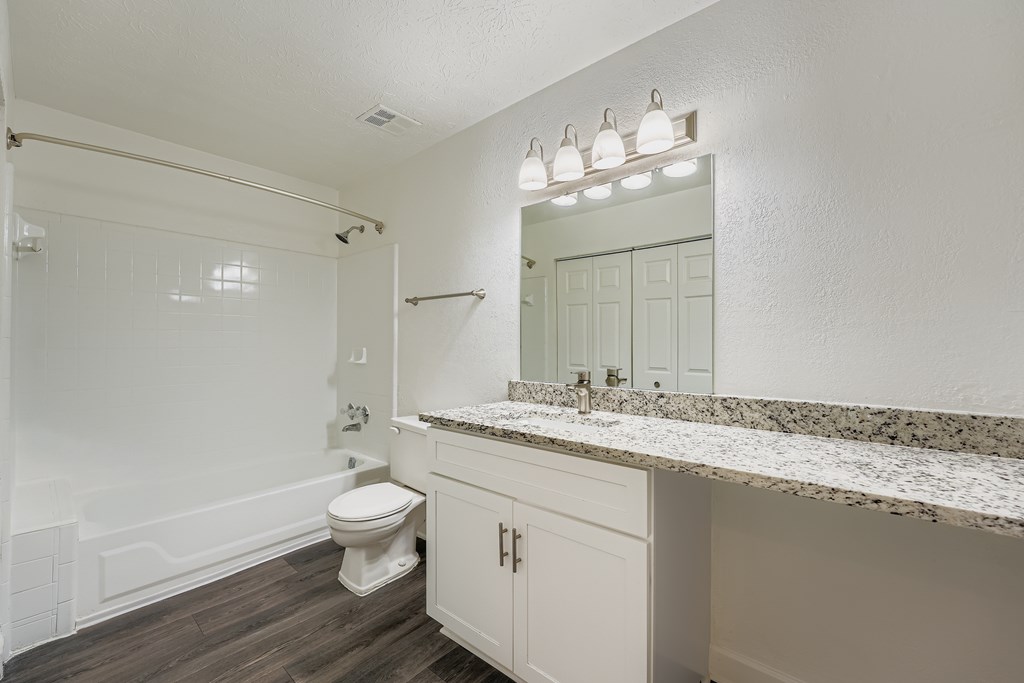 A white bathroom with a toilet, sink, and mirror.