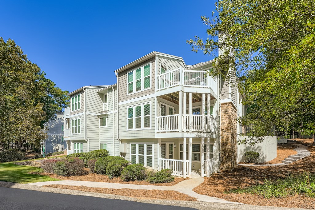 A large white house with a balcony and a tree in front.