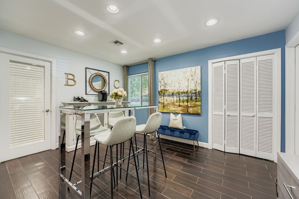 A dining area with a glass table and white chairs.