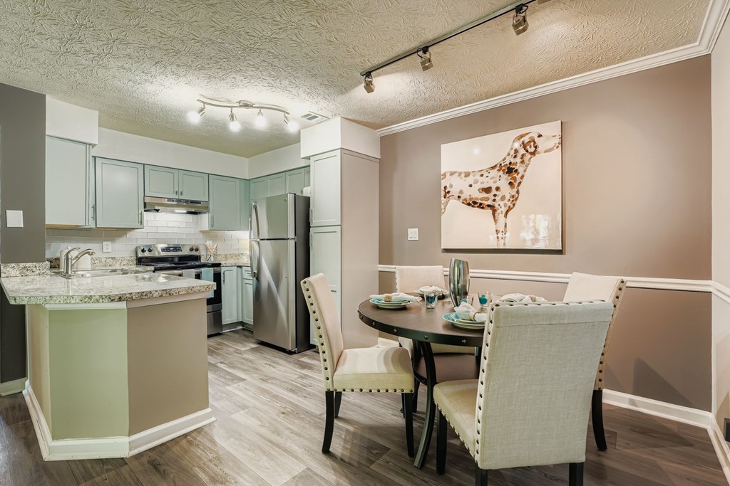 A kitchen with a table and chairs and a painting of a giraffe.