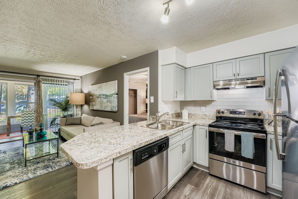 A modern kitchen with stainless steel appliances and a marble countertop.
