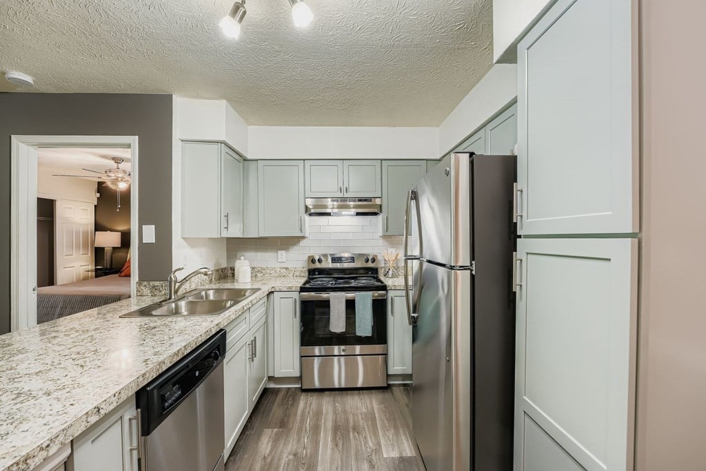 A kitchen with a refrigerator, sink, and stove.