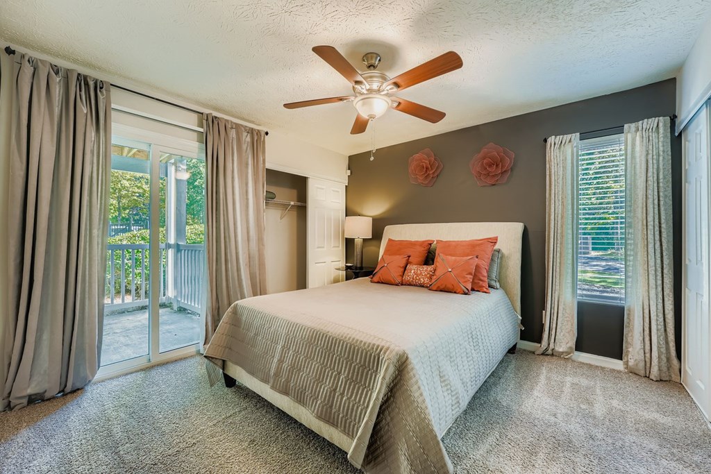 Bedroom with a bed, a ceiling fan, and a sliding glass door.