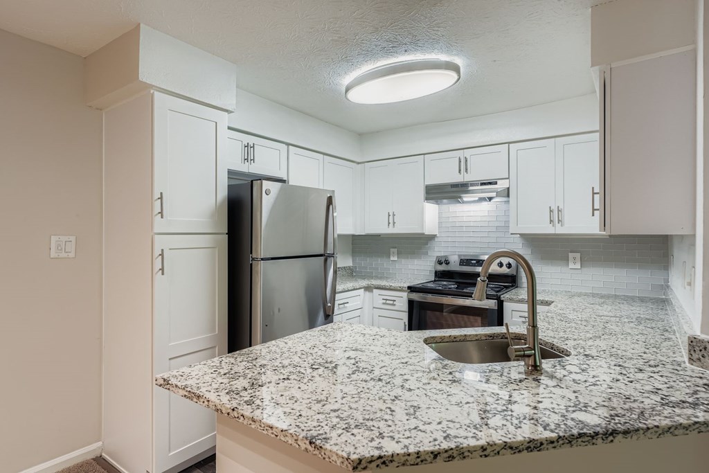 A kitchen with granite countertops and white cabinets.