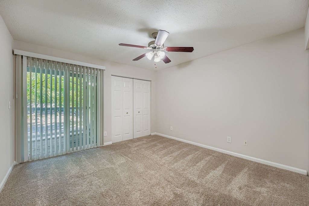 A room with a ceiling fan and carpeted floor.
