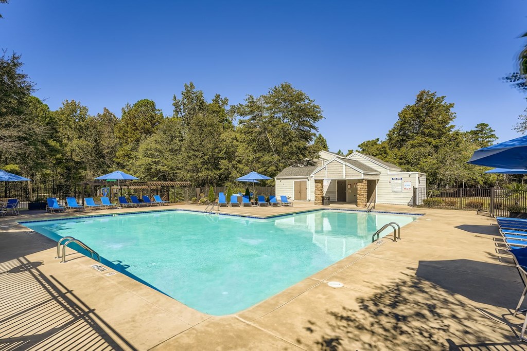 A large swimming pool surrounded by trees and a building in the background.