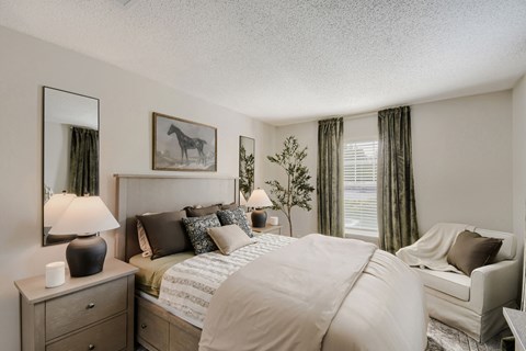 A bedroom with a large bed, a nightstand with a lamp, and a painting of a horse on the wall.