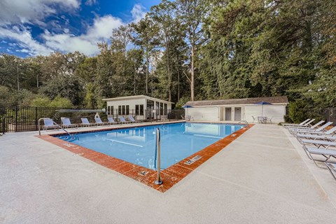 A large outdoor swimming pool surrounded by trees and lounge chairs.
